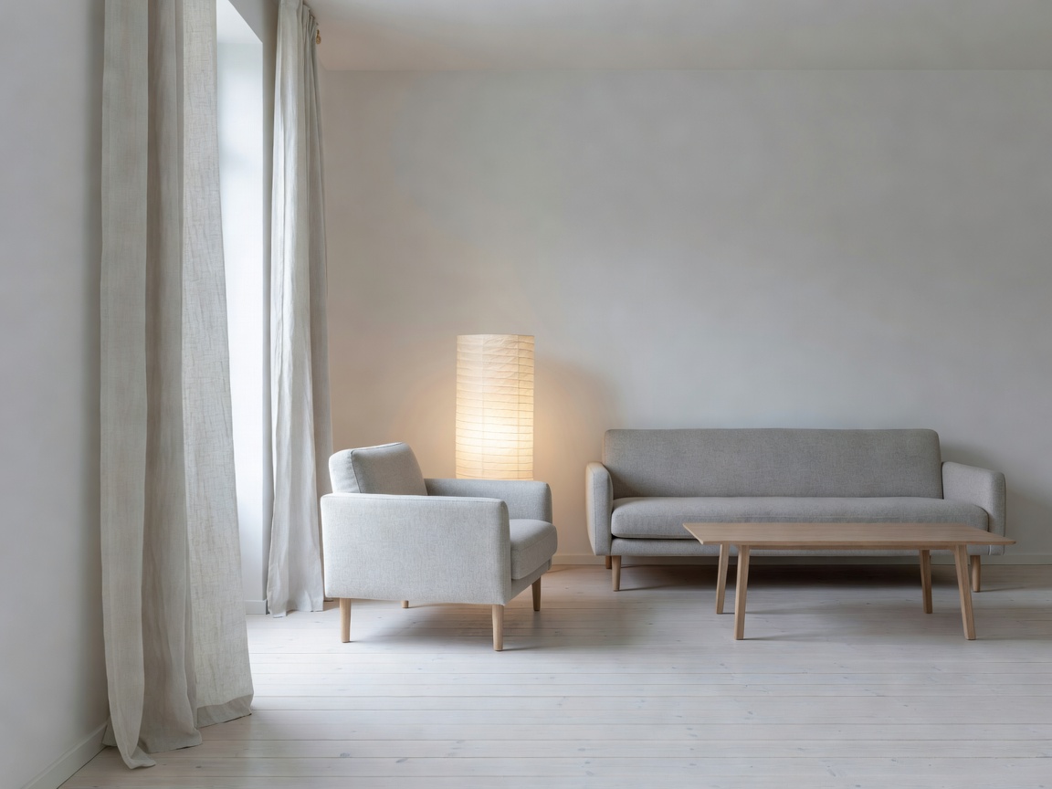 Quiet Scandinavian interior living space with pale whitewashed floorboards, tactile linen drapes, and paper lamp